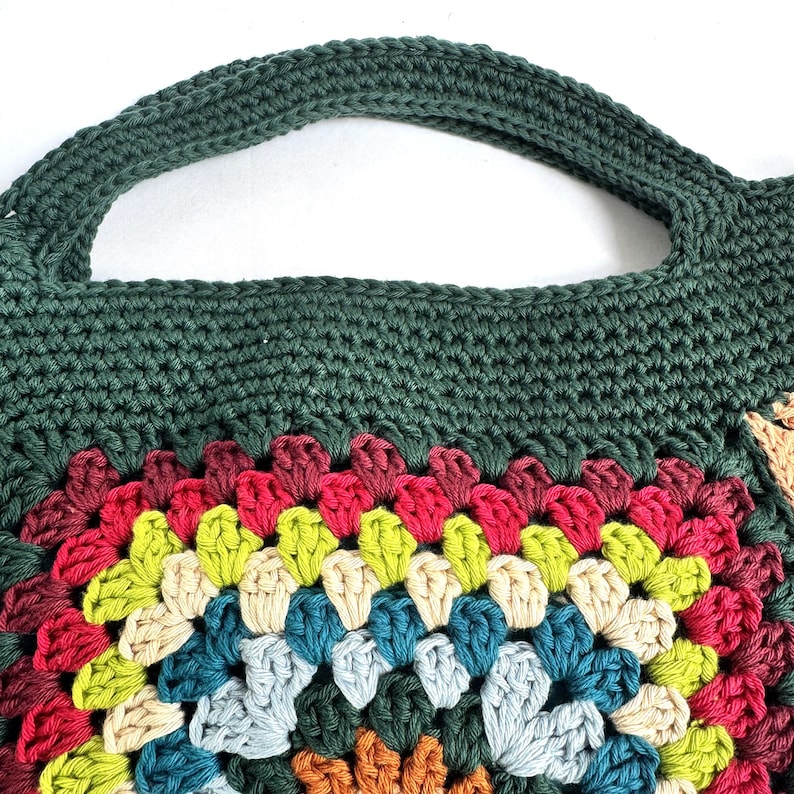 Puede incluir: Bolso tote de crochet hecho a mano con asa y parte superior verde oscuro. El bolso presenta un dise&ntilde;o de granny square colorido con tonos de rojo, amarillo, azul y crema. El bolso est&aacute; hecho de hilo suave, ideal para llevar objetos cotidianos.
