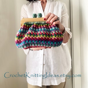 Peut inclure: Une pochette en crochet colorée avec un cadre en bois et des fermoirs en plastique vert. Le sac est tenu par une personne portant une chemise blanche. CrochetKnittingIdeas.etsy.com