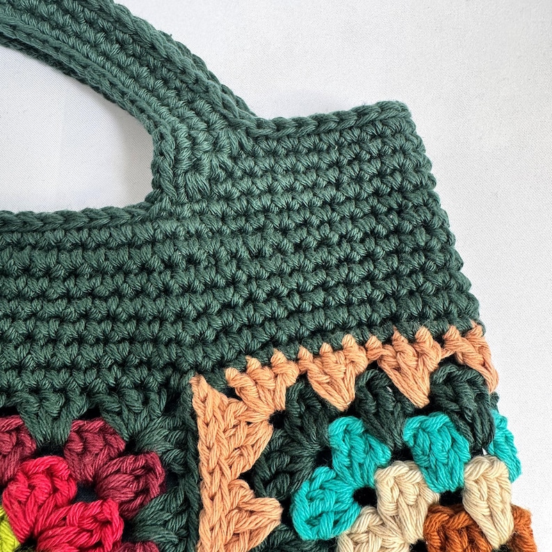 Puede incluir: Bolso tote de ganchillo hecho a mano en color verde oscuro. El bolso presenta un dise&ntilde;o de cuadrados de la abuela con cuadrados coloridos en rojo, turquesa, beige y marr&oacute;n. El asa es una parte integrada y resistente del bolso.