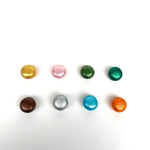 May include: Eight round, metallic buttons in various colors, including gold, pink, green, brown, silver, blue, and orange.