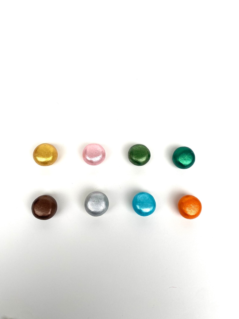 May include: Eight round, metallic buttons in various colors, including gold, pink, green, brown, silver, blue, and orange.