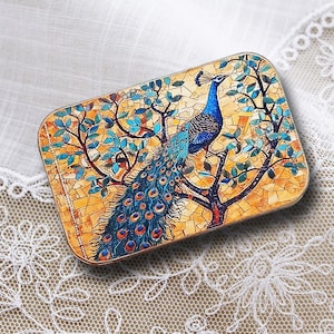 May include: Rectangular decorative box featuring a mosaic design of a peacock perched on a tree. The peacock has blue and teal feathers, with a yellow and orange background. The box has a gold trim.