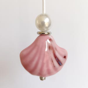 May include: A pink ceramic shell-shaped light pull with a white pearl and silver accents.