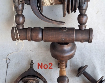 May include: A dark brown wooden spinning wheel flyer assembly labeled No1, featuring a central bobbin with wound yarn, and a separate detached flyer assembly labeled No2 with an additional wooden bobbin, all crafted from turned wood components.