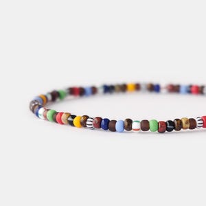 Könnte beinhalten: Ein farbenfrohes Perlenarmband mit einer Vielzahl von Farben, darunter Rot, Blau, Grün, Gelb und Braun.