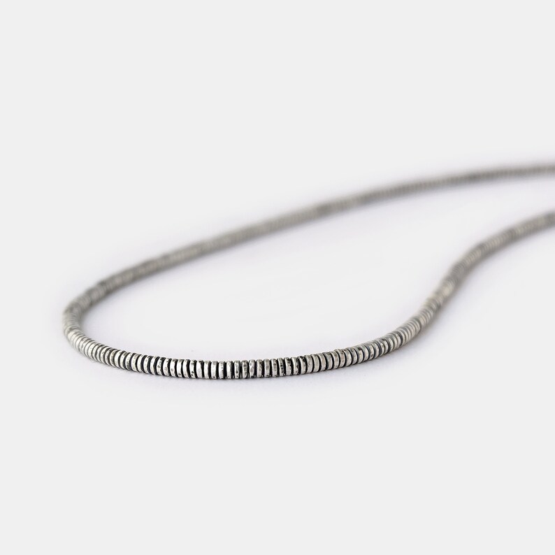 May include: A silver chain necklace made of small, round beads.