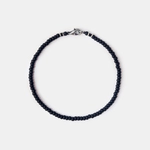 May include: A black beaded bracelet with a silver clasp.