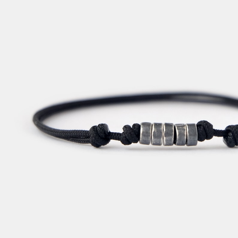 May include: A black cord bracelet with a row of silver beads.