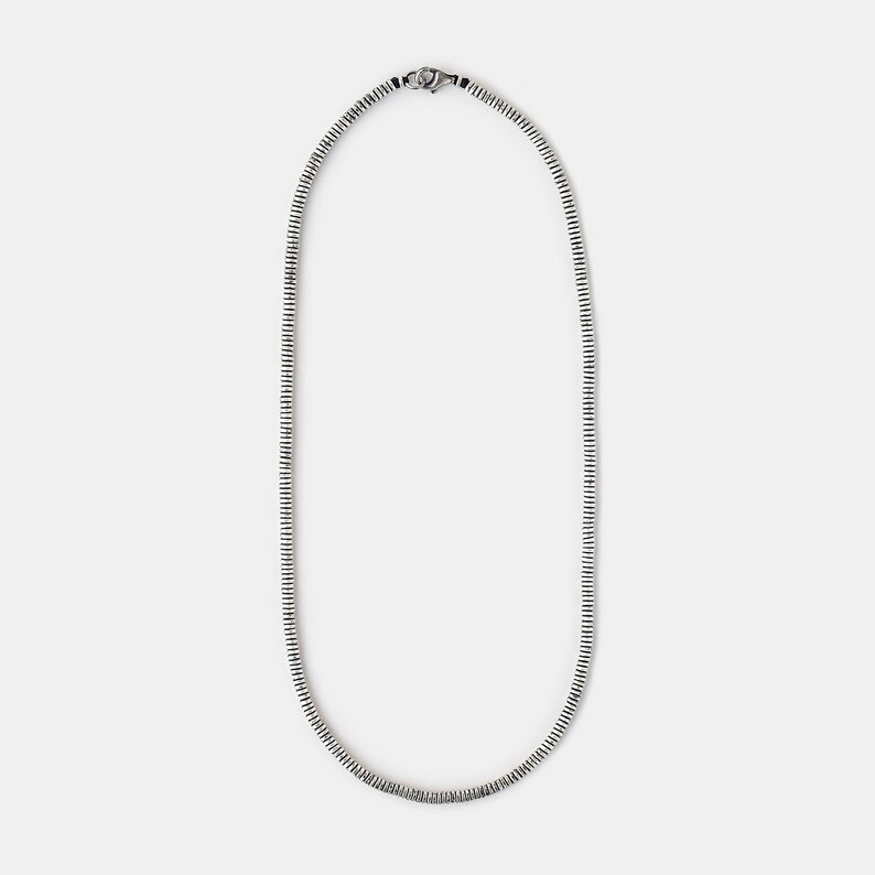 May include: A silver chain necklace with a simple design. The chain is made of small, linked circles.