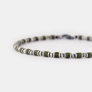 Könnte beinhalten: Ein silbernes und grünes Perlenarmband. Das Armband besteht aus kleinen, runden Silberperlen und größeren, rechteckigen grünen Perlen.