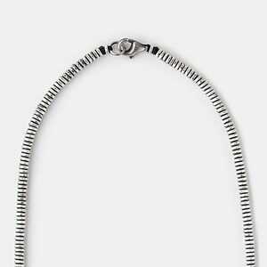 May include: A silver chain necklace with a textured, ridged design. The chain has a lobster claw clasp.