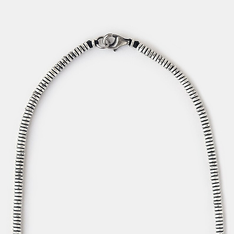 May include: A silver chain necklace with a textured, ridged design. The chain has a lobster claw clasp.