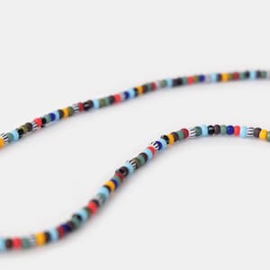 May include: A colorful beaded necklace with a mix of blue, red, yellow, green, black, and white beads.