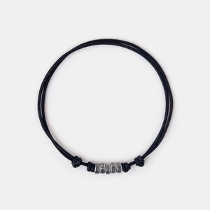 May include: A black cord bracelet with silver metal beads.