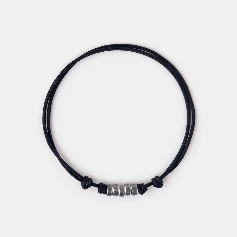 May include: A black cord bracelet with silver metal beads.