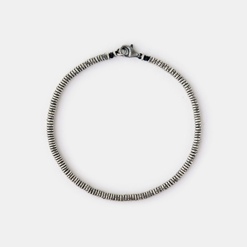 May include: A silver bracelet with a clasp closure. The bracelet is made of small, round beads.