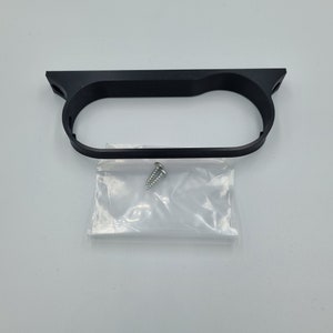 May include: Black plastic gauge pod mount with a single screw included in a clear plastic bag.