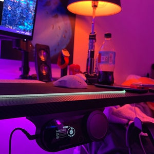May include: A black desk with a purple light strip and a black and silver desk controller with a screen that reads "SHARE 1/2/3/4" and "HIGH".