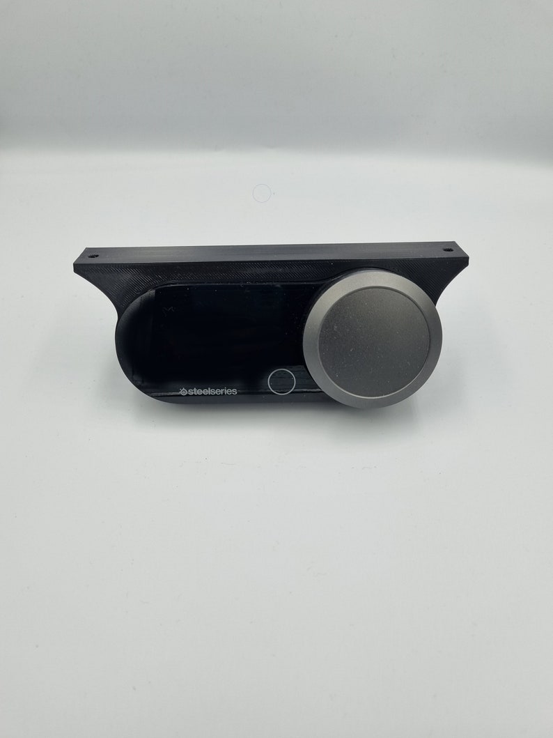 May include: A black SteelSeries device with a silver knob and a small digital display.