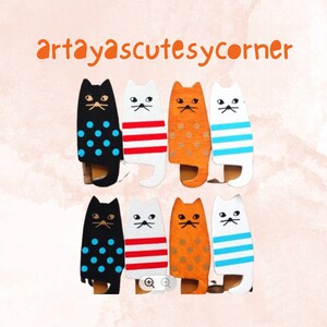 May include: Set of eight wooden cat figurines with different patterns. The cats are painted in black, white, red, and orange with blue, white, and red stripes and polka dots.