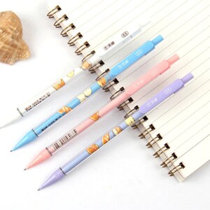 May include: Five colorful mechanical pencils with a white background. The pencils have a clear barrel with a cute cartoon design and a colored tip. The pencils are arranged in a row, with the tips pointing to the right.