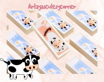 May include: A set of white rectangular tiles with a blue and white cow design. The tiles have the word "mooing" printed on them. The tiles are arranged in a random pattern on a white background.