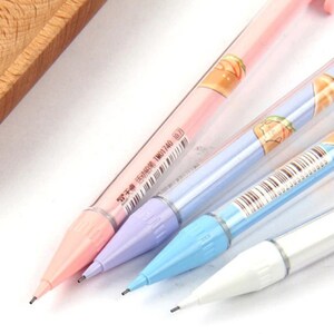 May include: Four colorful mechanical pencils with cartoon characters and text on the barrels. The pencils are pink, light blue, purple, and white.