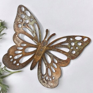 May include: A rusty brown metal butterfly wall decor with cut-out details. The butterfly has a distressed finish and is a great addition to any home decor.