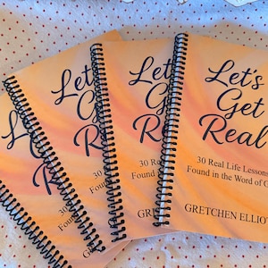 May include: Four spiral-bound books with orange covers. The covers feature the text "Let's Get Real" in a cursive font, along with the subtitle "30 Real Life Lessons Found in the Word of God." The author's name, Gretchen Elliott, is also visible.