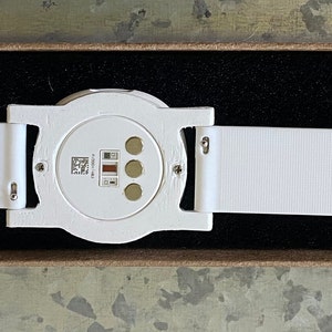 This is the underside of the adapter showing the adapter, the optional watch band, and an attached Ava Fertility Tracker 2.0 (tracker not included in this listing).