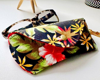 May include: A black and green floral patterned glasses case with a red hibiscus flower and a gold button closure.