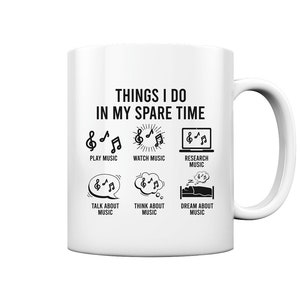 Könnte beinhalten: Eine weiße Keramiktasse mit einem schwarzen Design, auf dem "Things I do in my spare time" steht und Aktivitäten im Zusammenhang mit Musik aufgelistet sind, darunter Musik spielen, Musik schauen, Musik recherchieren, über Musik sprechen, über Musik nachdenken und von Musik träumen.