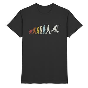 Könnte beinhalten: Schwarzes T-Shirt mit einem Retro-Grafikdesign, das die Entwicklung des Menschen bis zu einer Person auf einem Roller zeigt. Das Design verwendet eine Reihe von Figuren in Orange, Gelb, Blau und Weiß auf schwarzem Hintergrund.
