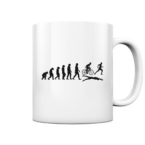 Può includere: Una tazza in ceramica bianca con una silhouette nera dell'evoluzione di un essere umano da una scimmia a un triatleta. Il triatleta sta nuotando, andando in bicicletta e correndo.