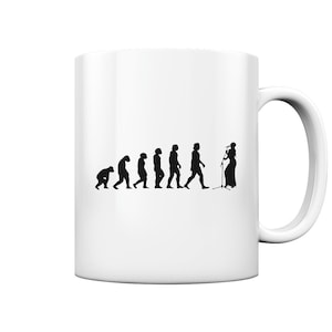 Op de afbeelding: Witte keramische mok met een zwart silhouet van de evolutie van de mens, eindigend met een persoon die in een microfoon zingt. De tekst "Evolution of a Singer" staat op de mok gedrukt.