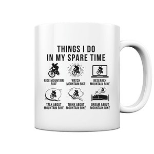 Peut inclure: Une tasse en céramique blanche avec une illustration en noir et blanc d'un cycliste de montagne. Le texte "THINGS I DO IN MY SPARE TIME" est en haut de la tasse. L'illustration montre un cycliste de montagne qui roule, regarde, recherche, parle, pense et rêve de vélo de montagne.