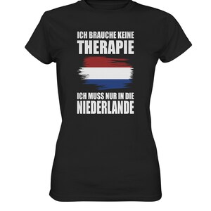 Może przedstawiać: Czarny T-shirt z białym tekstem, który brzmi "Ich brauche keine Therapie Ich muss nur in die Niederlande" i stylizowaną flagą holenderską.