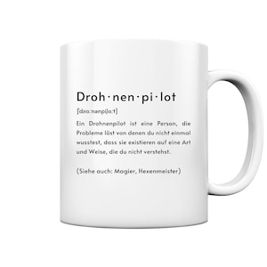 Könnte beinhalten: Weißer Keramikbecher mit gebogenem Henkel. Der Becher hat schwarzen Text mit der Aufschrift "Drohnen pilot" mit phonetischer Aussprache und einer Definition auf Deutsch. Der Becher hat eine Standardgröße.