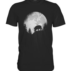 Puede incluir: Una camiseta negra con un gráfico de un jabalí caminando frente a una luna llena y árboles.