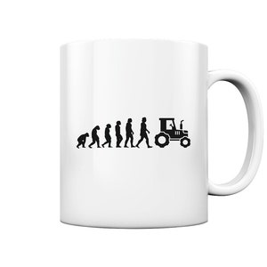Könnte beinhalten: Weiße Keramiktasse mit einer schwarzen Grafik, die die Entwicklung des Menschen zeigt und in einem Traktor endet. Das Design zeigt eine Entwicklung vom Affen zum Menschen, die mit einer Traktorsilhouette endet. Die Tasse hat einen gebogenen Griff.