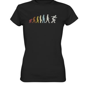 Puede incluir: Una camiseta negra con un gráfico de estilo vintage de la evolución de los humanos que termina con una persona patinando. El gráfico está en tonos de azul, verde, amarillo y naranja.