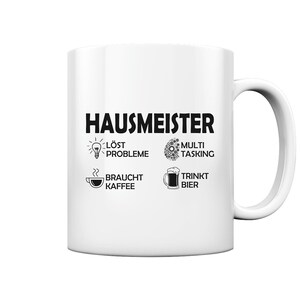 Könnte beinhalten: Weiße Keramiktasse mit schwarzem Design, auf dem "Hausmeister" steht und Symbole für Problemlösung, Multitasking, Kaffeetrinken und Biertrinken abgebildet sind.