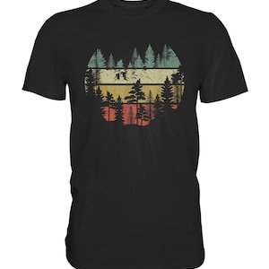 Könnte beinhalten: Schwarzes T-Shirt mit einem Vintage-Grafikdruck einer Waldsilhouette vor einem Sonnenuntergang.