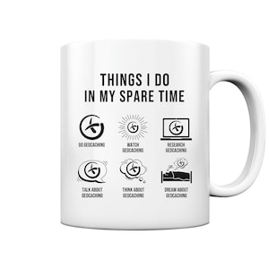 May include: White ceramic mug with a black design that says "Things I do in my spare time" and shows a series of icons related to geocaching.