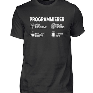 Op de afbeelding: Zwart T-shirt met witte tekst die "PROGRAMMIERER" luidt en vier pictogrammen. De pictogrammen tonen een gloeilamp met de tekst "LÖST PROBLEME", een tandwiel met de tekst "MULTI TASKING", een koffiekopje met de tekst "BRAUCHT KAFFEE" en een bierglas met de tekst "TRINKT BIER".
