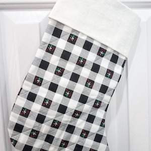 May include: A black and white checkered Christmas stocking with a white cuff and a red and green holly pattern.