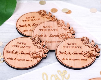 May include: Four round wooden save the date magnets with a floral design and the text "Save the Date" and "Jack & Sarah" with the date "18th August 2022".