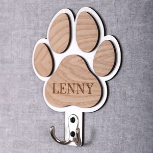 May include: White wooden paw print with a hook, the paw print is made of five separate pieces of wood, the center piece has the name "LENNY" engraved on it.