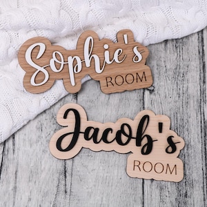 May include: Two wooden signs with the names "Sophie's Room" and "Jacob's Room" written in black and white lettering.