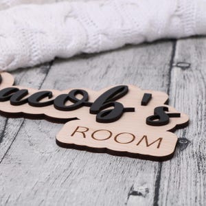 May include: A wooden sign with the text "Jacob's Room" in black lettering. The sign is on a light wood background.